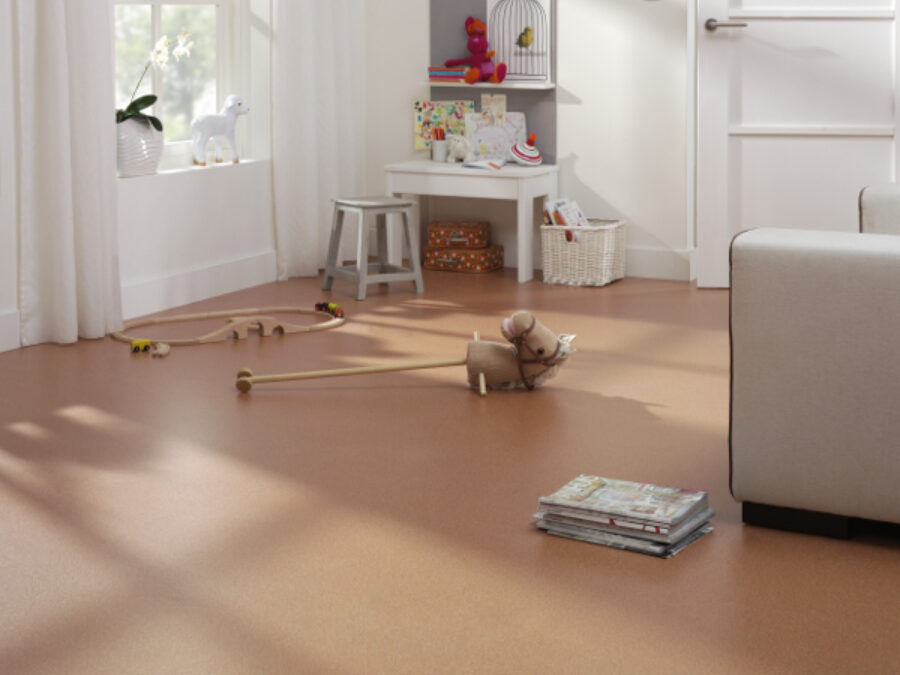 Woonkamer met naadloze vinylvloer in beige, kamerhoge gordijnen en relaxfauteuil