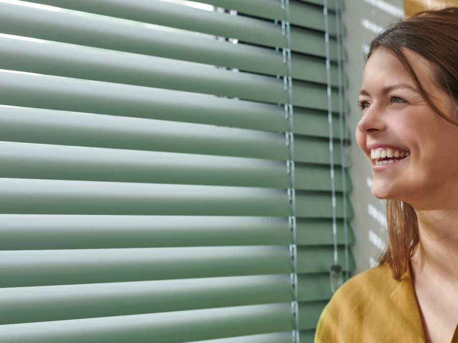 Groene horizontale jaloezieën met blije dame.