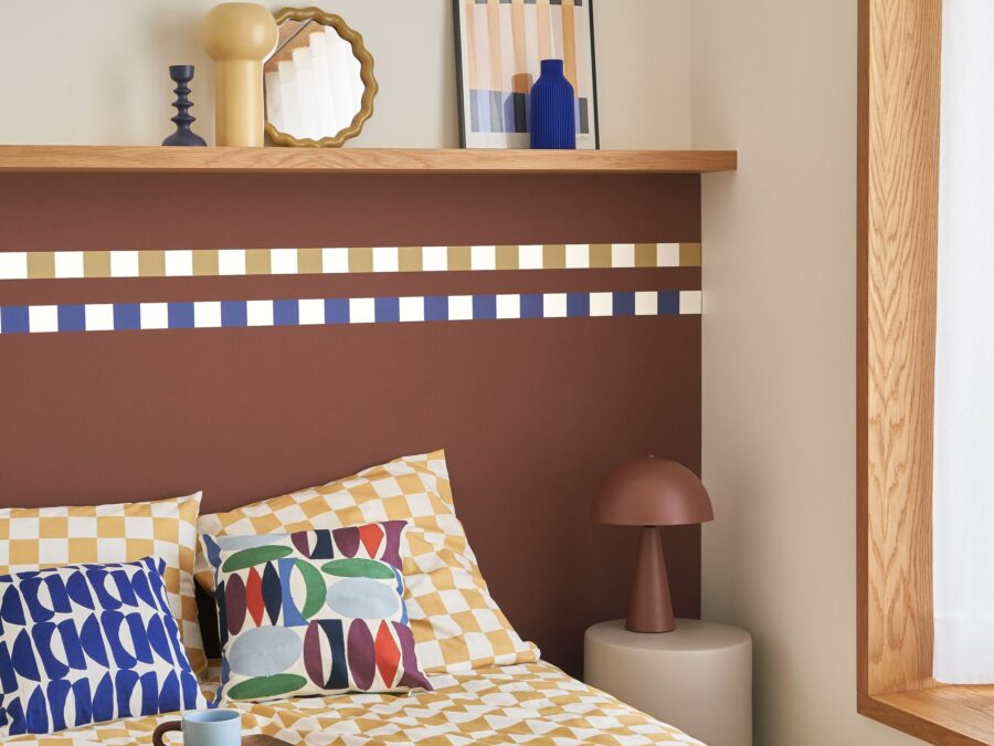 Slaapkamer in warme sfeer met terracotta behang en grafische details