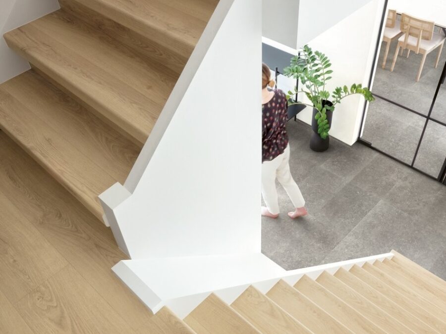 Hal met witte wanden, trapbekleding van houtlook laminaat en vloer van grijze laminaat tegels, natuurlijke stijl