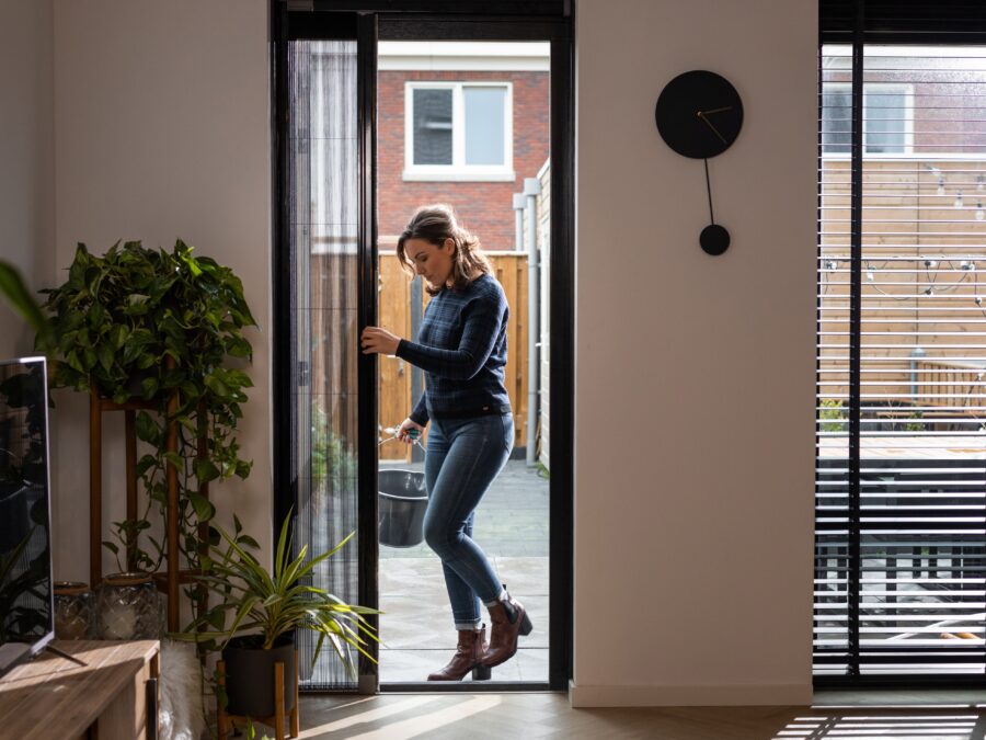 Zwarte plissehordeur met vrouw in woonkamer