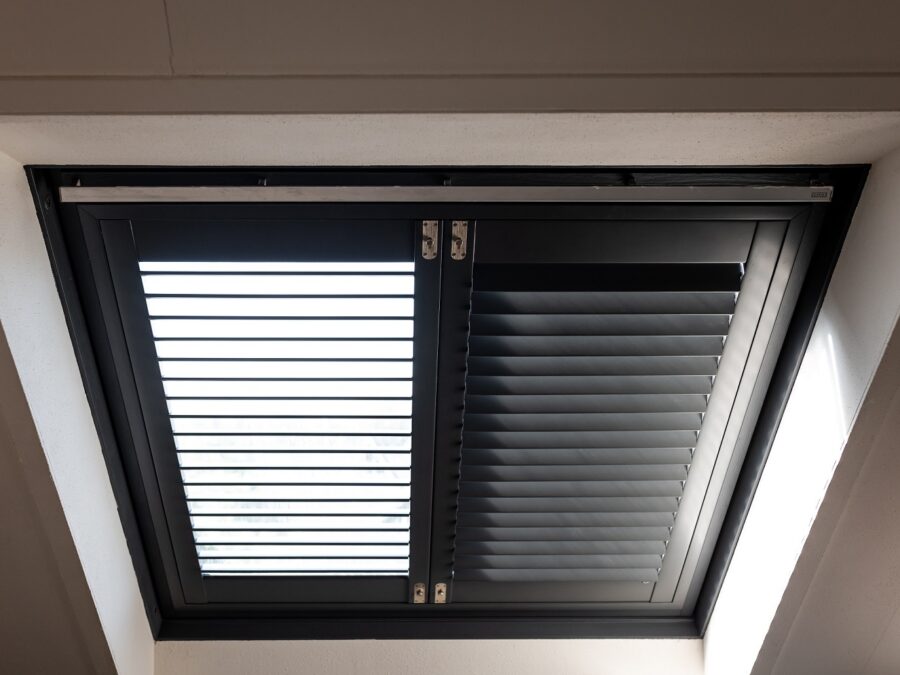 Detail dakraam, draaikiep raam met zwarte houten shutters.