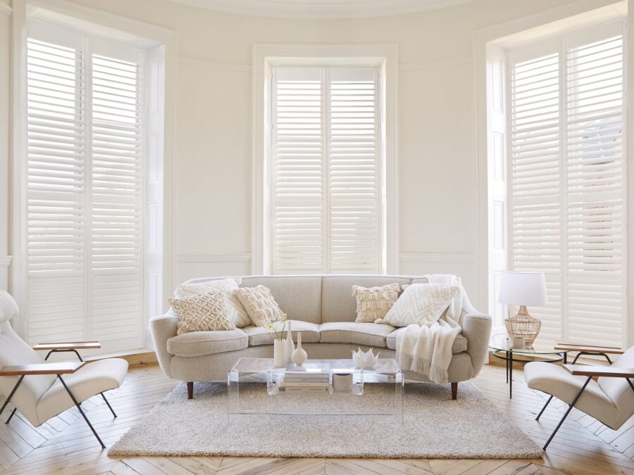 Witte shutters in woonkamer met hoge ramen