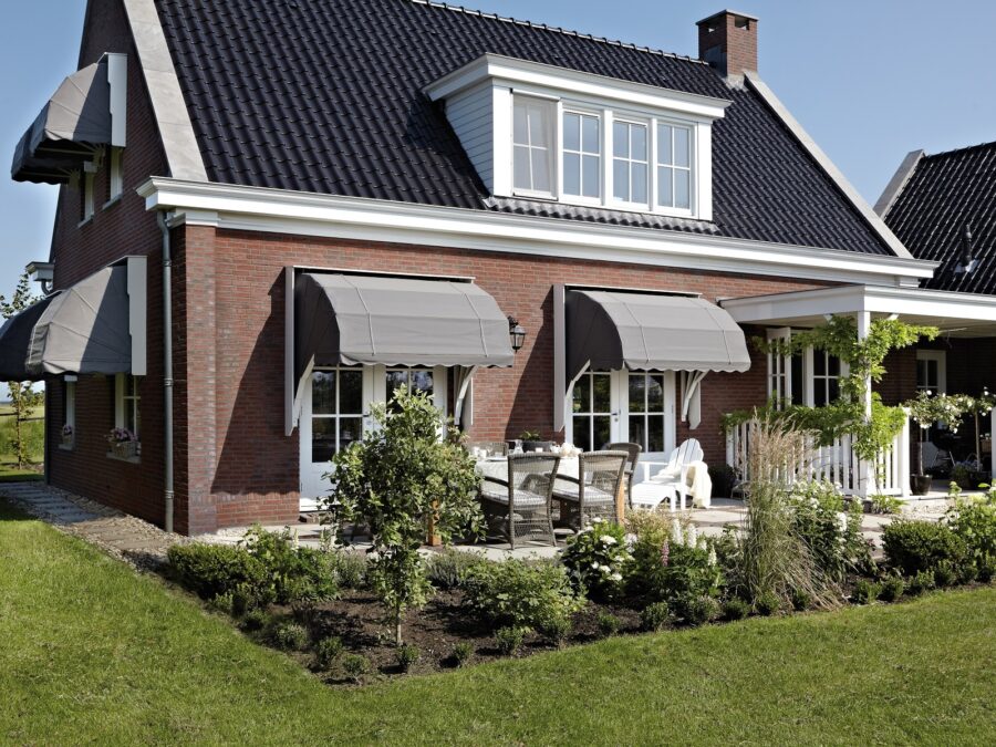 Grijze markiezen bij vrijstaand huis met witte kozijnen en tuin