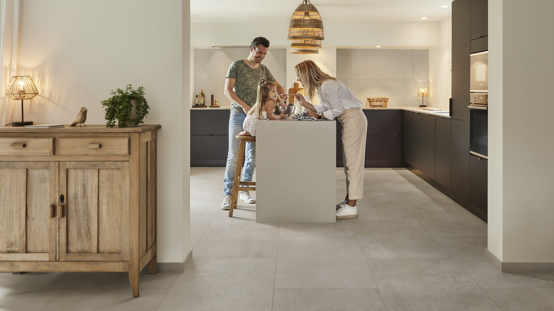 Keuken met grote pvc-vloer tegels in lichtgrijs, zwarte keukenkasten, keukenblok met gezin en sfeerverlichting.