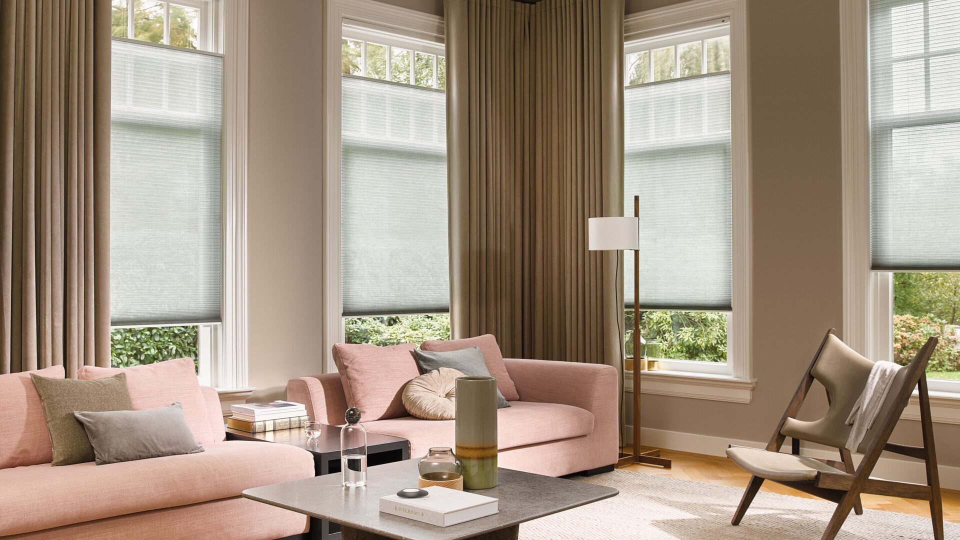 Kamerhoge gordijnen op elektrische gordijnrails in een sfeervolle woonkamer met een grote bank met bijpassend vloerkleed.