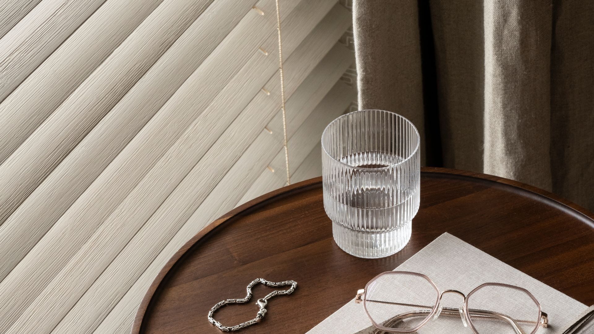 Sfeerfoto van witte houten jaloezieën naast bijzet tafeltje