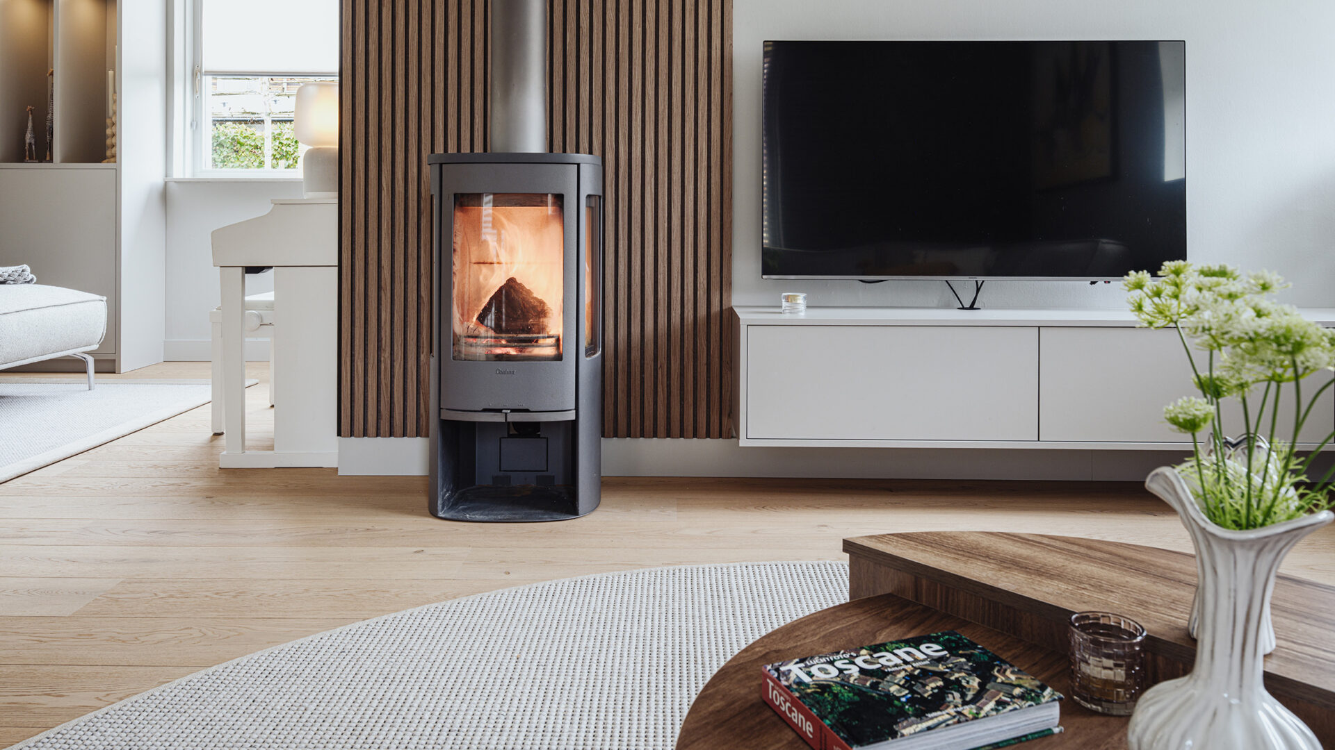 Woonkamer met bruine wandpanelen, een lichtgrijze zwevende tv-meubel en een rond wollen vloerkleed