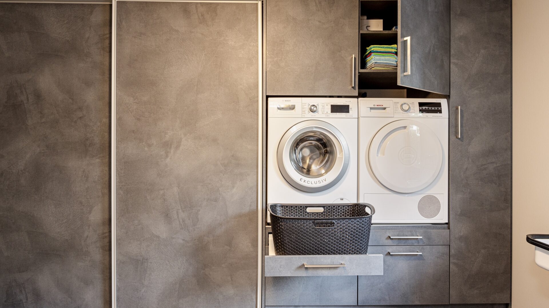 Grijze wasmachine kast met plankje voor wasmand en opbergruimte met draai- en schuifdeur
