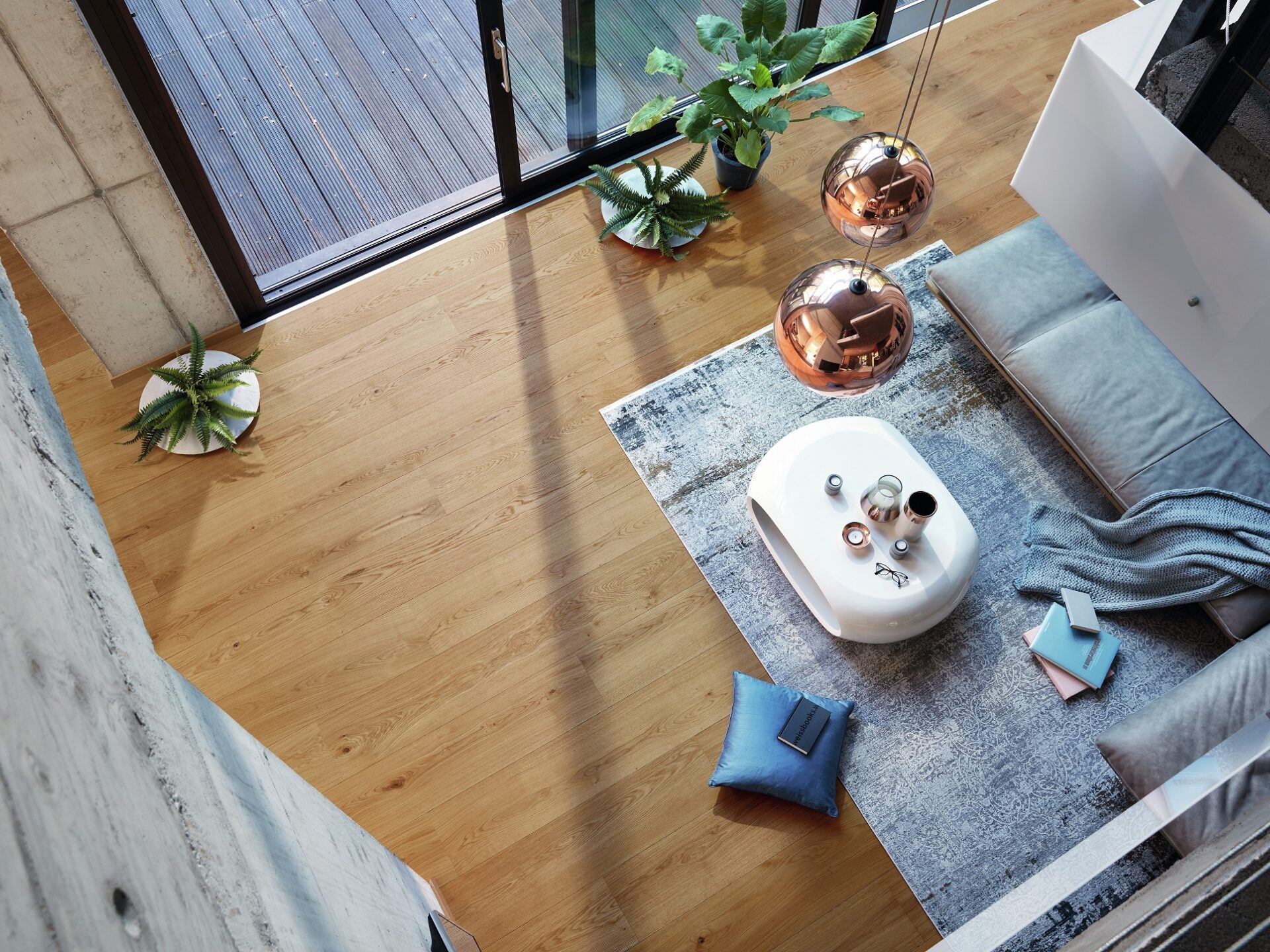 Ruime woonkamer moderne stijl met grijze loungebank, koperen lampen en laminaat in een warme bruintint.