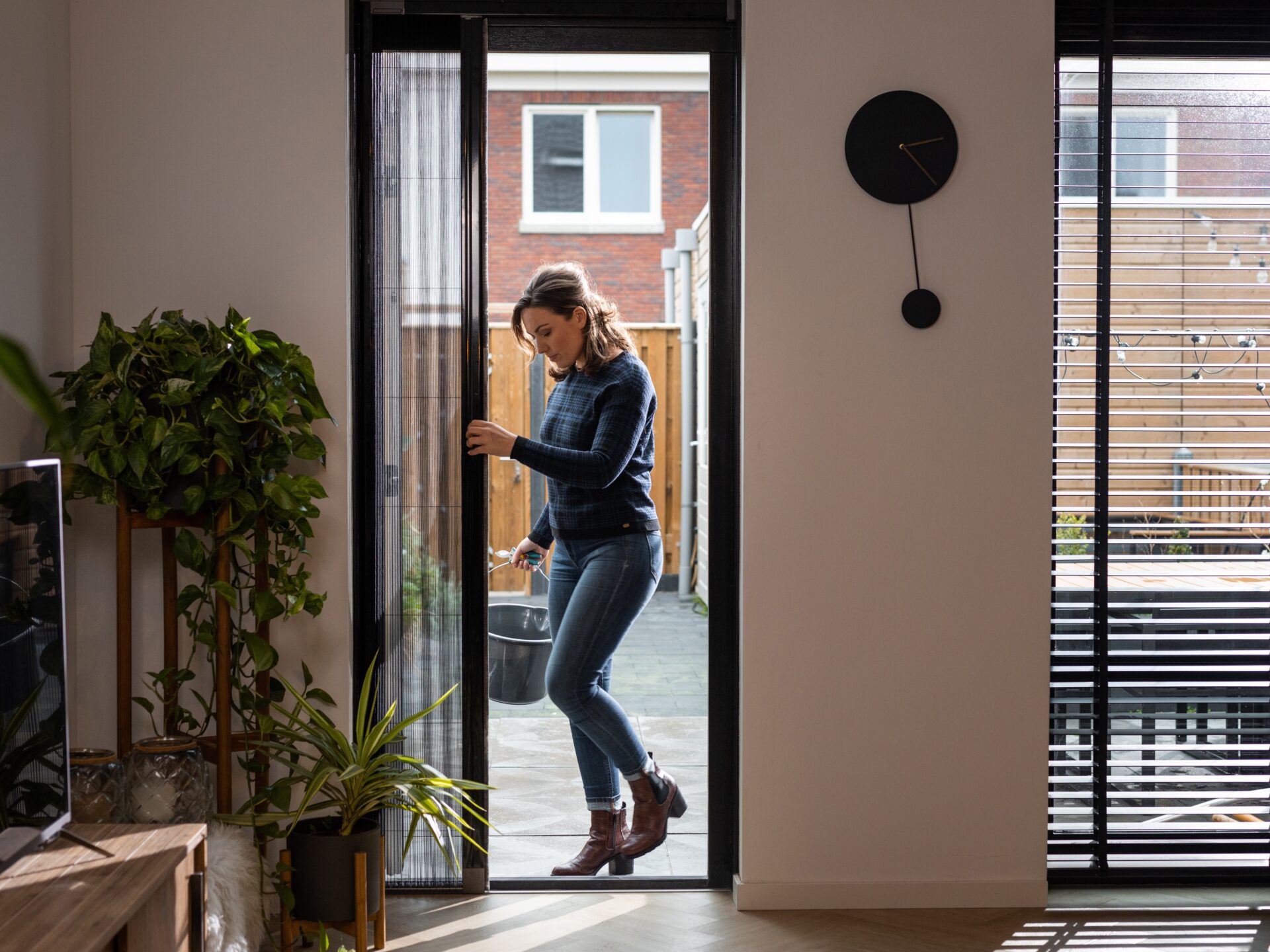 Zwarte plissehordeur met vrouw in woonkamer