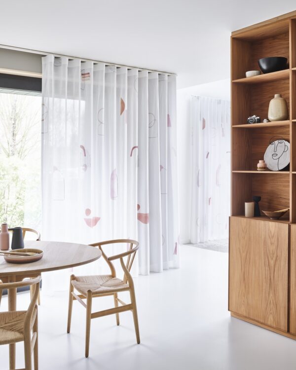 Een lichte eetkamer met doorzichtige witte vitrages met grafische print voor schuifpui.