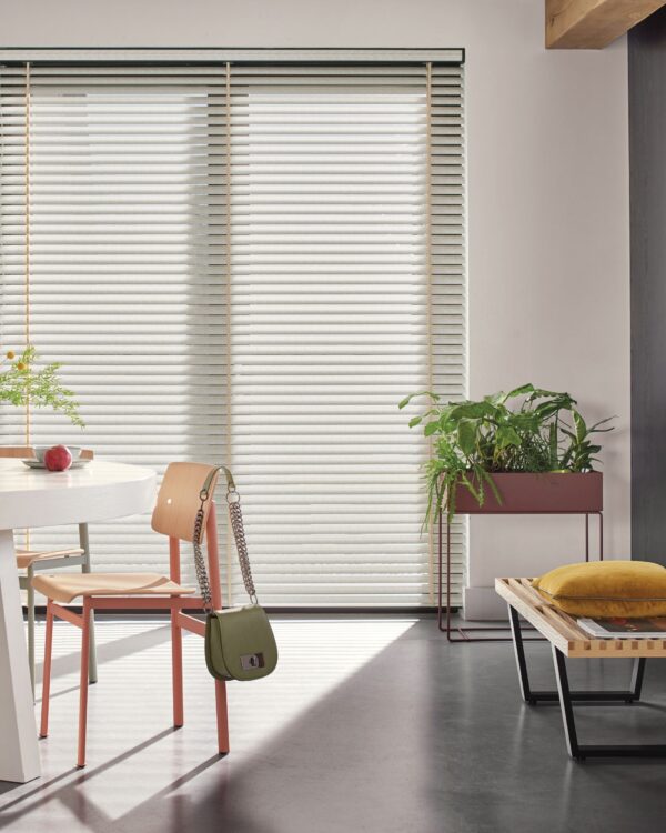 Loftstijl interieur met brede aluminium jaloezieën in lichtgroen en betonnen vloer