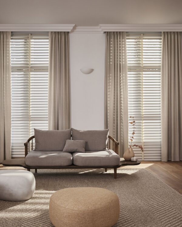 Woonkamer met aluminium jaloezieën in warme wit tint en beige overgordijnen