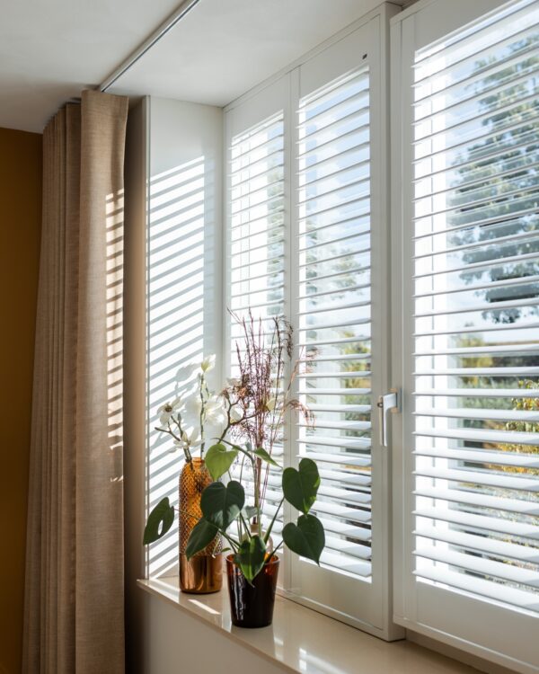 Lichte woonkamer met gordijnen en shutters