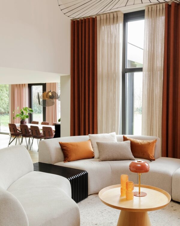 Bruine overgordijnen en beige inbetweens in de woonkamer