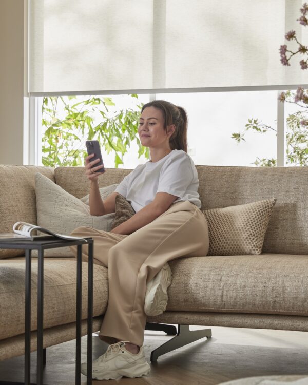 Vrouw bedient raamdecoratie met Apple Home-app op iPhone