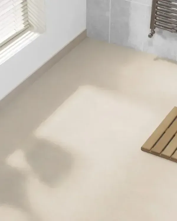 Badkamer met lichte beige marmoleumvloer, houten badmat, witte wastafel en handdoekradiator