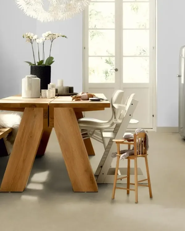 Keuken met lichte beige marmoleumvloer, houten eettafel met bank, kinderstoel en witte keukenkastjes