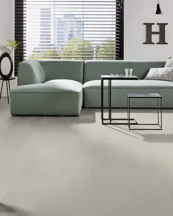 Moderne woonkamer met lichtgrijze marmoleumvloer, mintgroene hoekbank en zwarte bijzettafels