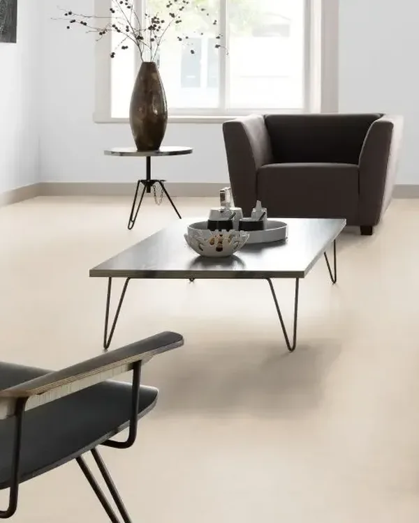 Lichte woonkamer met crèmekleurige marmoleumvloer, bruine fauteuil, lage salontafel en witte schouw