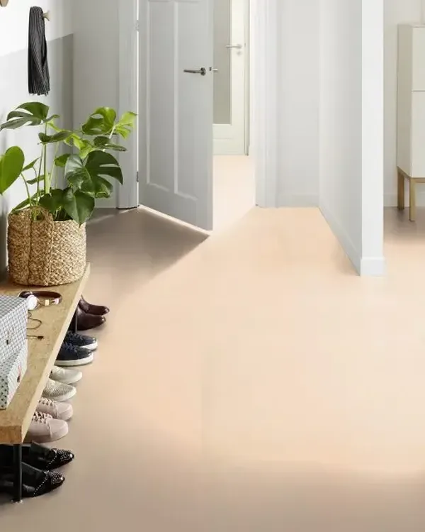 Lichte gang met zandkleurige marmoleumvloer, houten schoenenbank, plant in rieten mand en witte deuren
