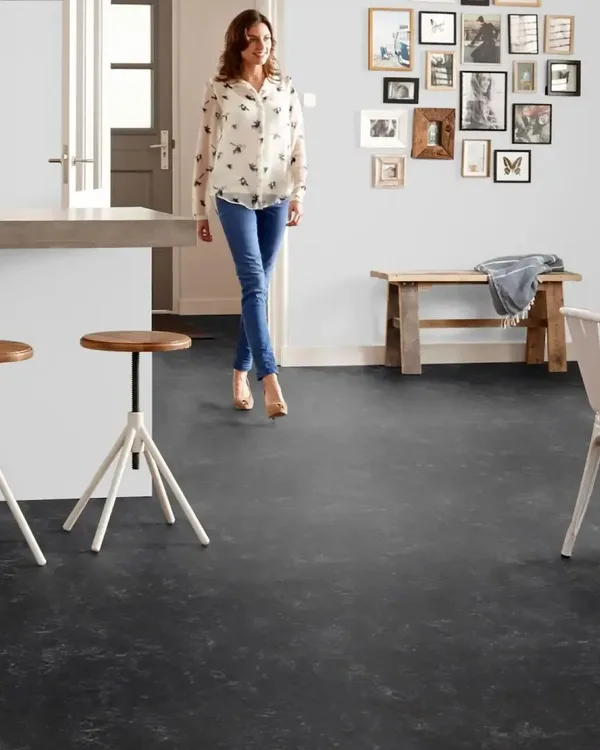 Open keuken en eethoek met zwarte Marmoleum Fresco Black vloer, houten bar met krukken en witte stoelen