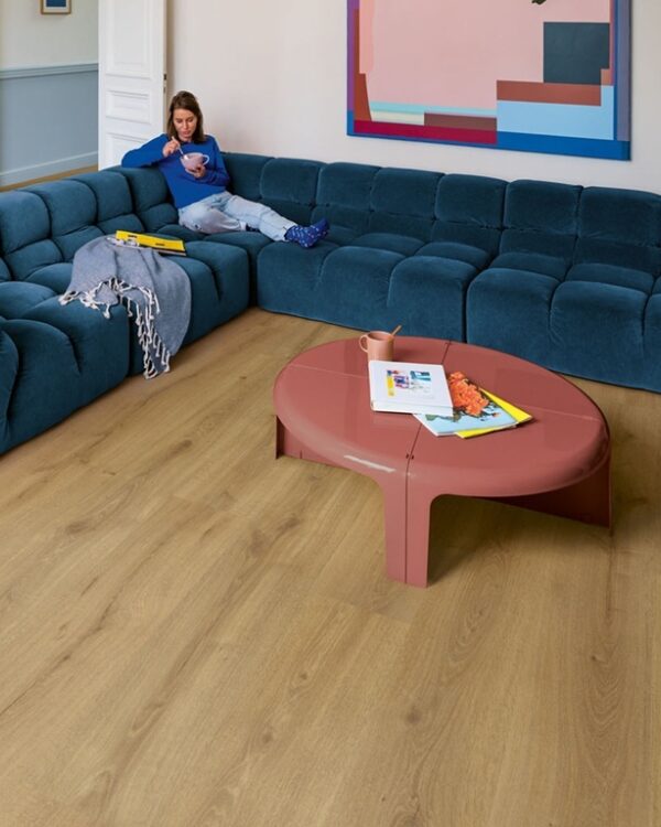 Woonkamer met blauwe hoekbank en houtlook laminaat in warme eikenkleur