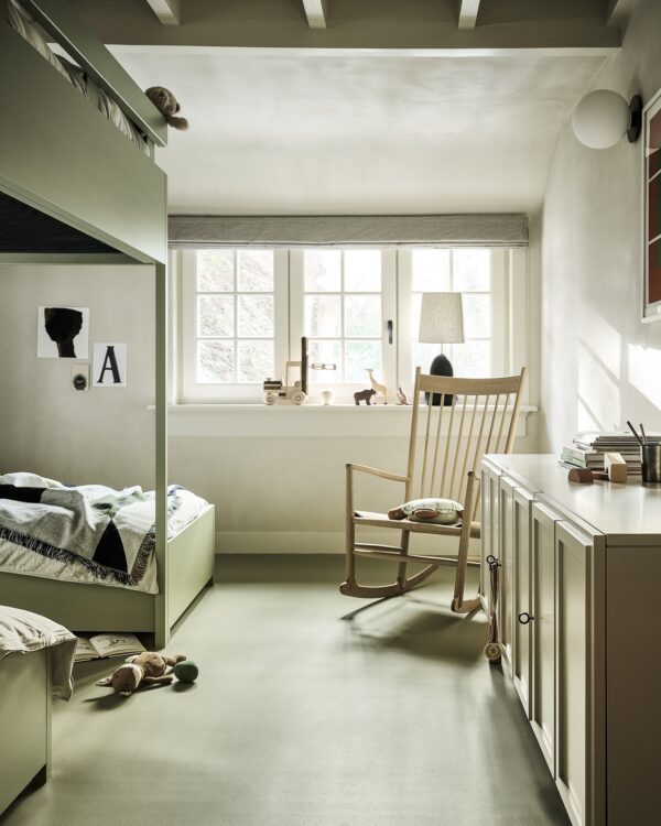 Kinderkamer met marmoleum vloer, houten dressoir en schommelstoel