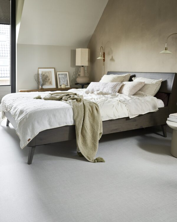 Moderne slaapkamer met rustige kleuren en strakke betonlook vloer.