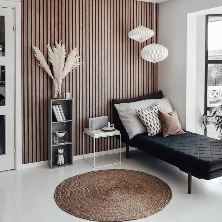 Sfeervolle woonkamer met chaise longue, moderne verlichting en statement muur met akoestische panelen van hout.