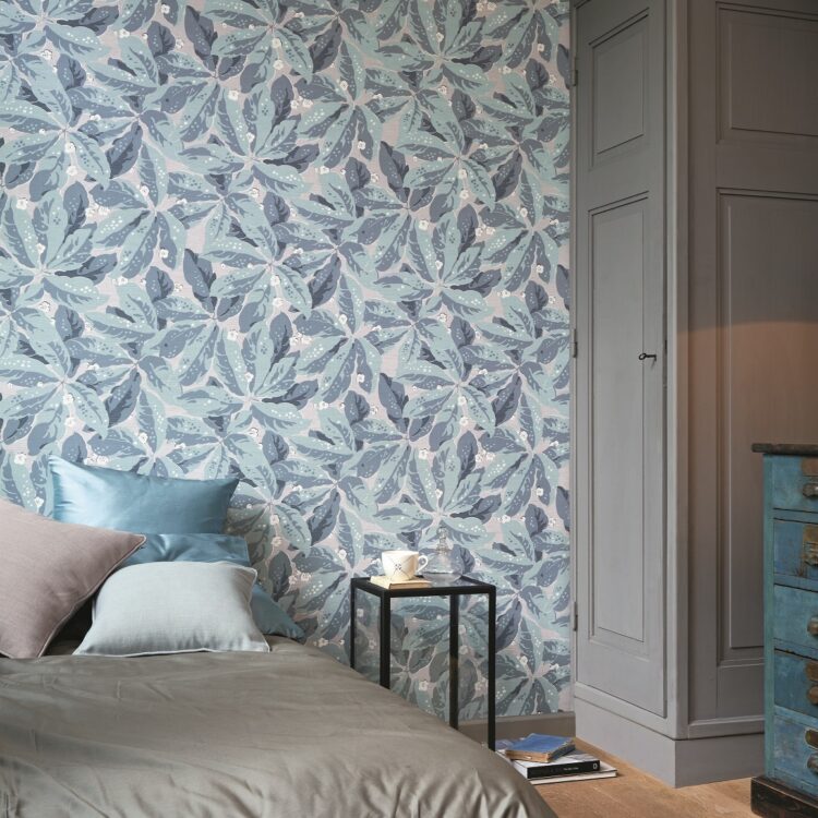 Gezellige slaapkamer met blauwgrijs Casadeco behang met print en houten meubelen. Thuisin