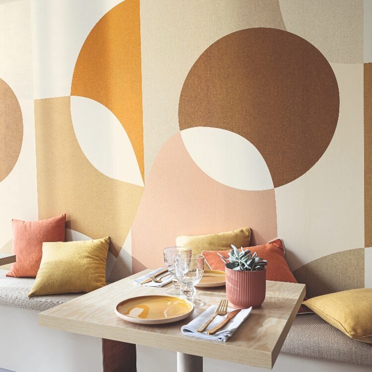 Behang van Caselio Molly, meerkleurig geel, oranje bruin in circels achter de eettafel op de muur
