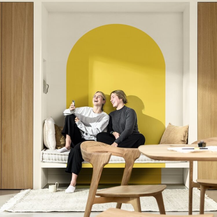 Eethoek in Scandinavische stijl met houten meubelen, lichtgrijze gietvloer en muurverf in wit en geel, True Joy Flexa kleur van het jaar 2025.