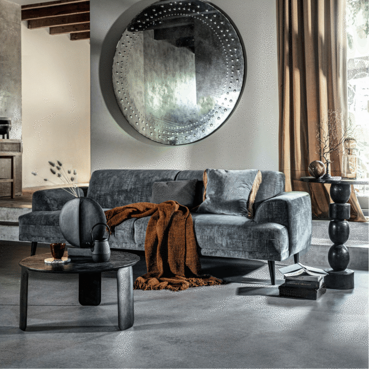 Betonlook vloer in de woonkamer met een velvetbank en sfeervol kleed