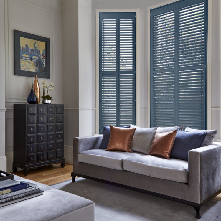 Luxe woonkamer met grote ramen en houten shutters in grijsblauw