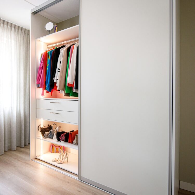 Witte kledingkast met schuifdeuren, hangplek, vakken en verlichting in de kast
