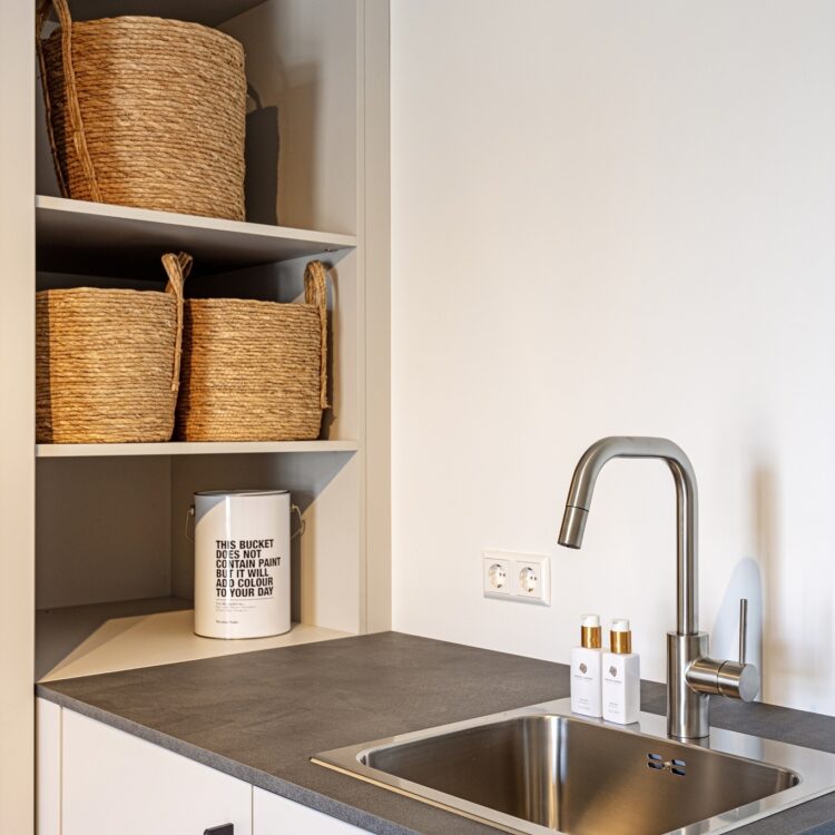 Witte wasmachine kast op maat met kraan in wasruimte