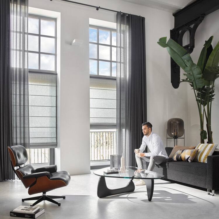 Vouwgordijn en vitrages in industrieel loft met man