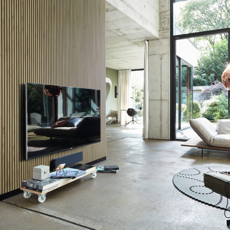 Woonkamer met grijze gietvloer en lichtbruine houten wandpanelen