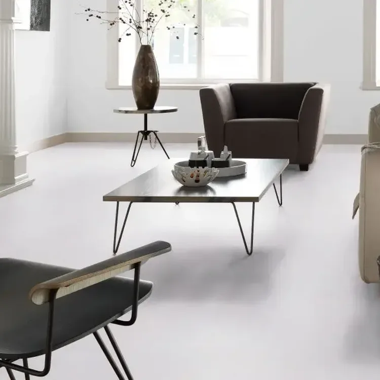 Lichte woonkamer met lichtgrijze marmoleumvloer, bruine fauteuil, lage salontafel en witte schouw