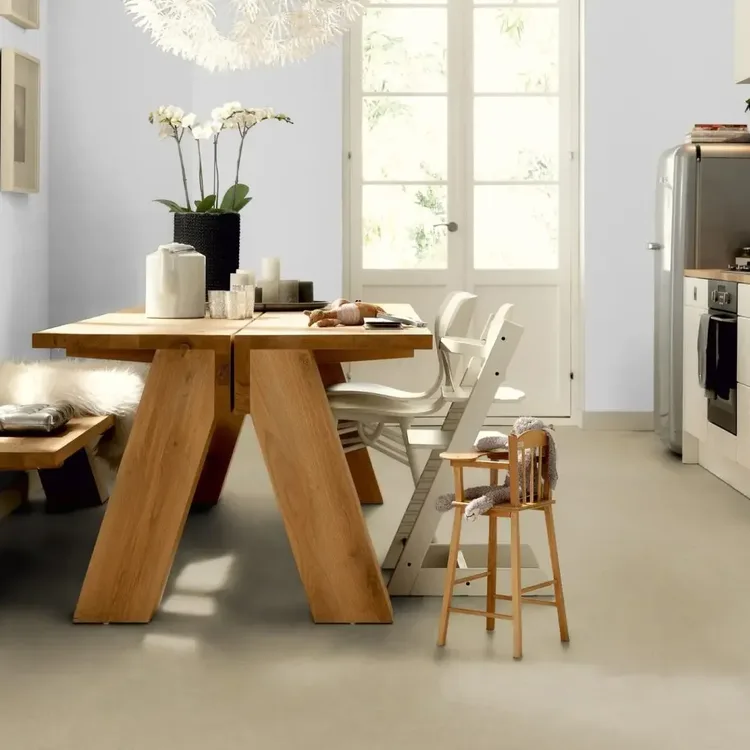Keuken met lichte beige marmoleumvloer, houten eettafel met bank, kinderstoel en witte keukenkastjes