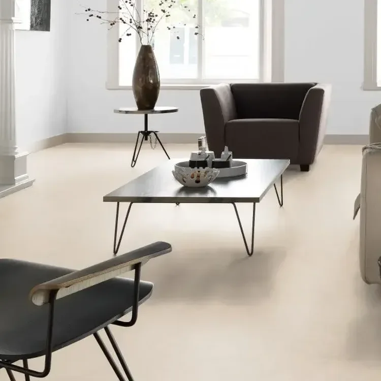 Lichte woonkamer met crèmekleurige marmoleumvloer, bruine fauteuil, lage salontafel en witte schouw