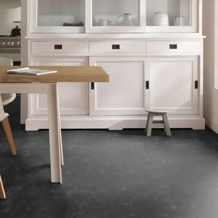 Keuken met grijze marmoleumvloer, witte buffetkast en houten eettafel met witte stoelen