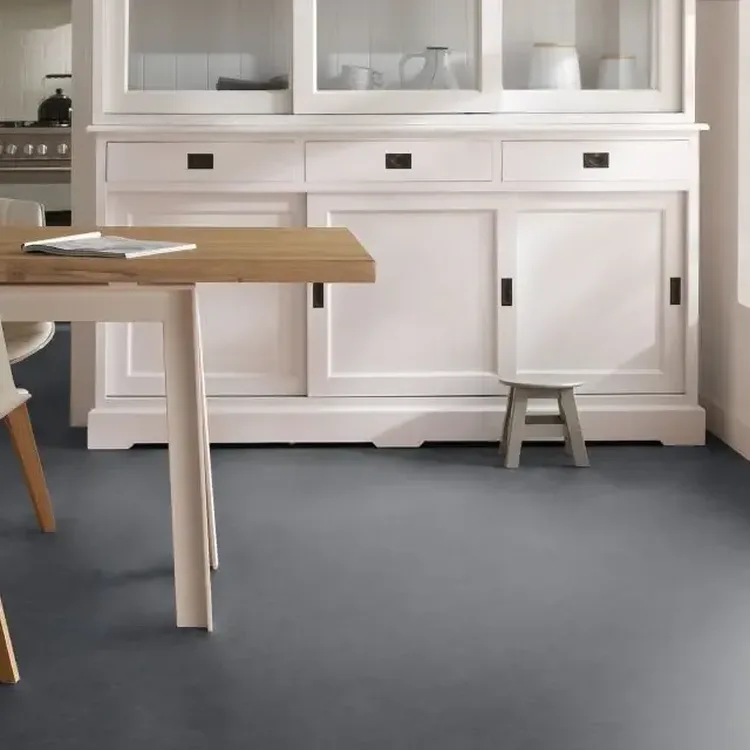 Keuken met grijze marmoleumvloer, witte buffetkast en houten eettafel met witte stoelen