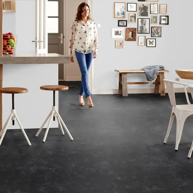 Open keuken en eethoek met zwarte Marmoleum Fresco Black vloer, houten bar met krukken en witte stoelen