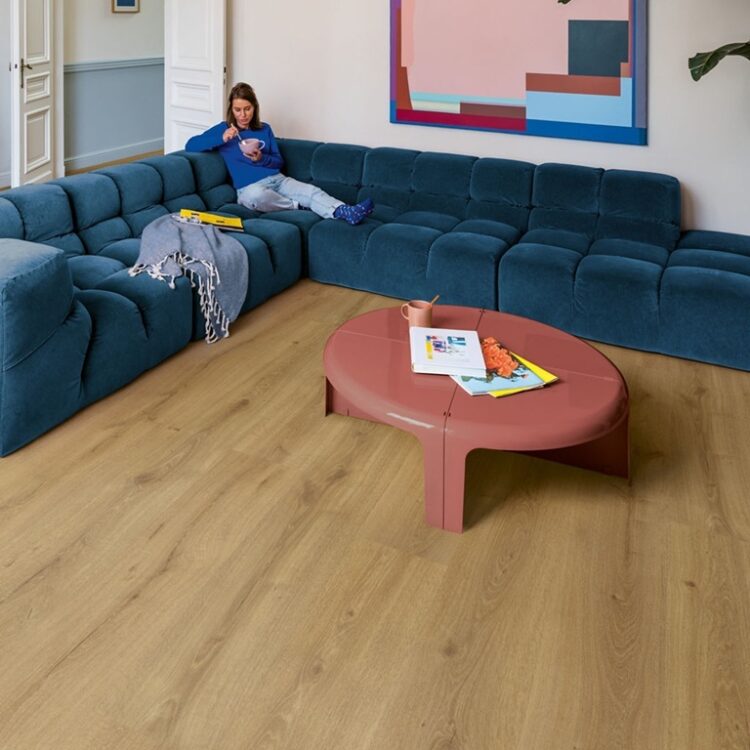 Woonkamer met blauwe hoekbank en houtlook laminaat in warme eikenkleur