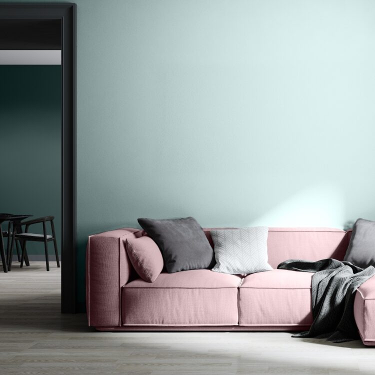 Woonkamer met comfortabele hoekbank in roze, houten vloer en blauwe tinten muurverf.