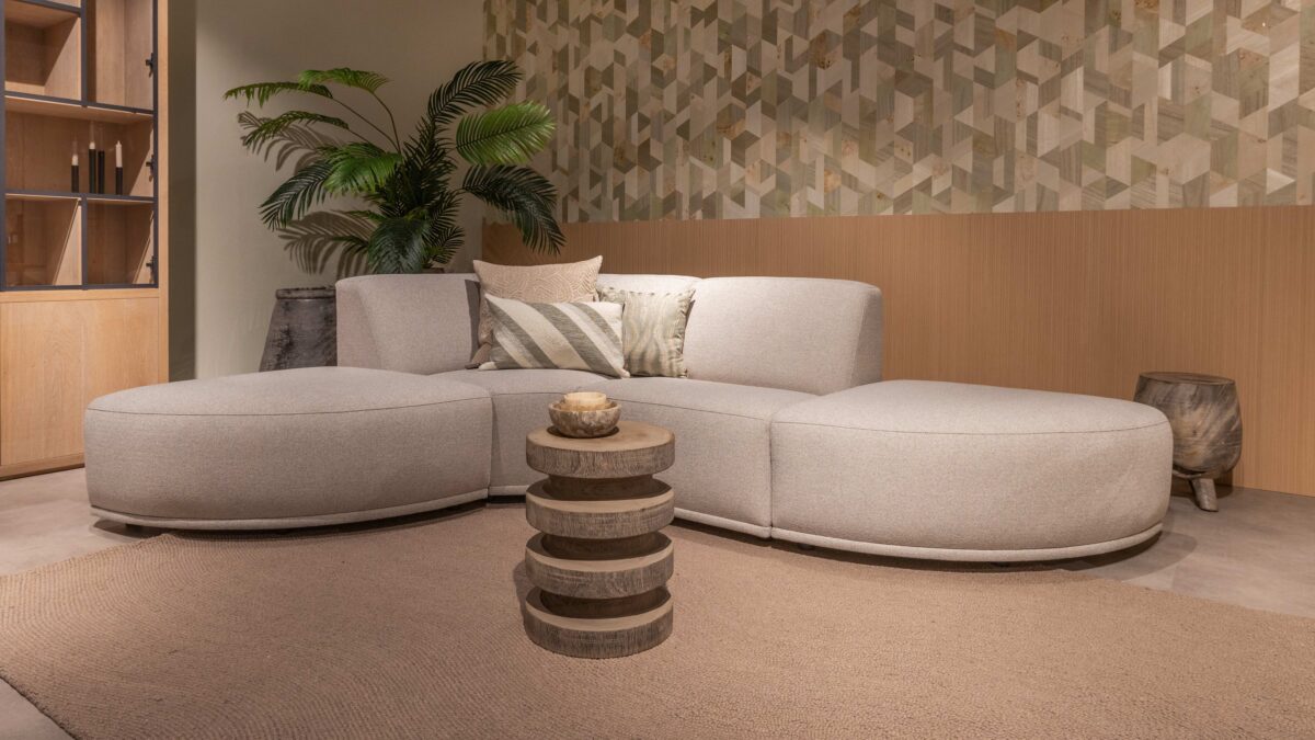 Woonkamer met Arte behang en lichten eiken wandpanelen en grijze hoekbank met beige vloerkleed